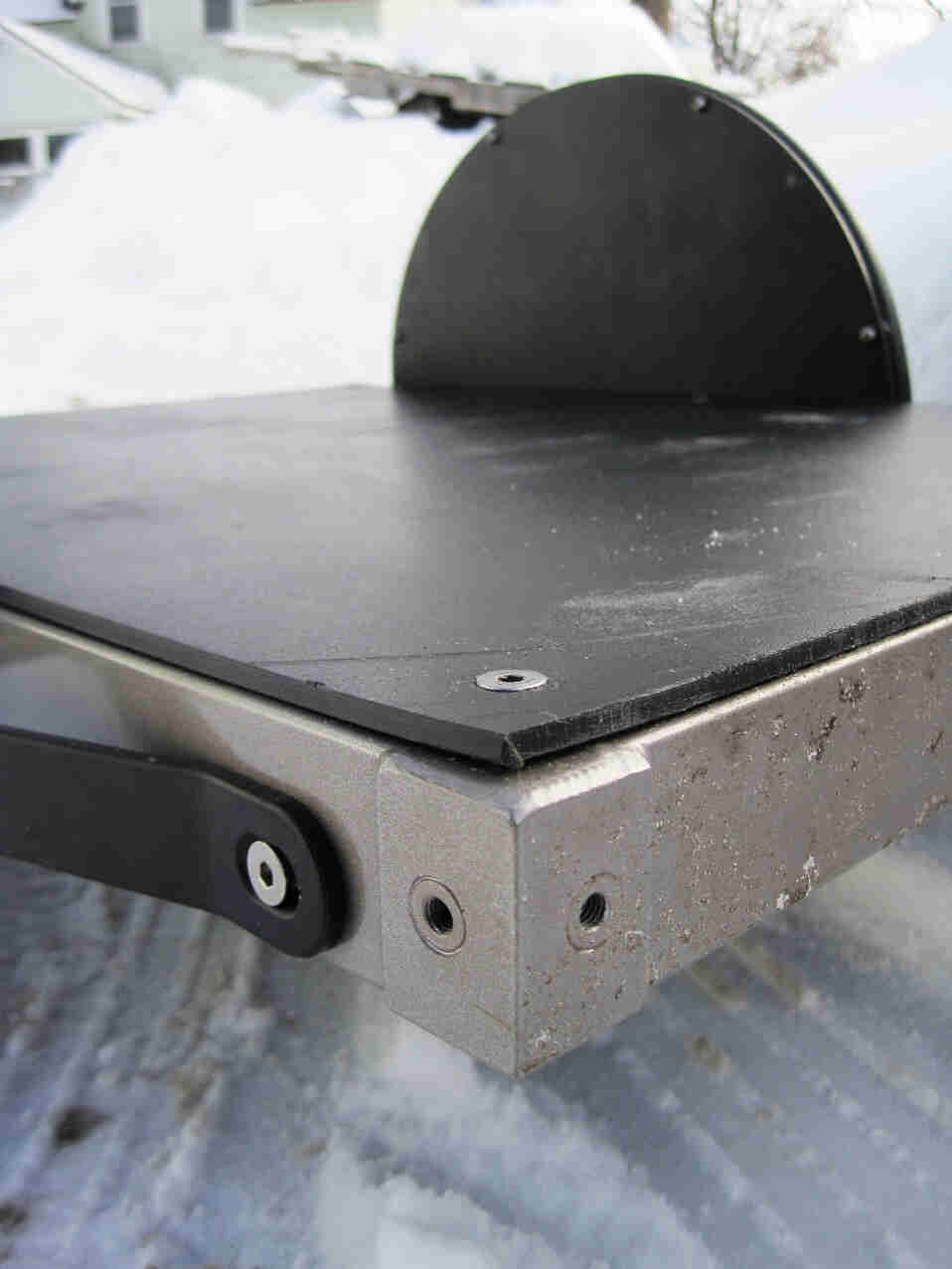 Rear, left side view of the corner detail from a  Surly Ted bike trailer with a flat deck, parked on snowy ground